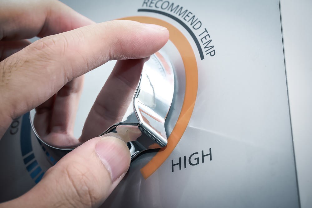 A homeowner adjusts the temperature on a hot water heater