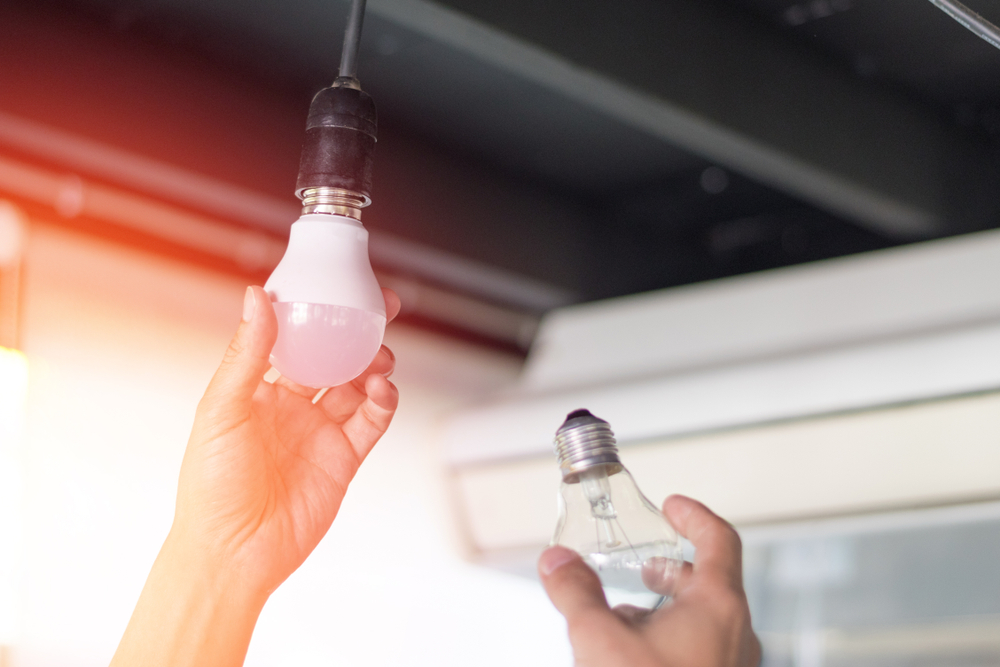 A person changes an old light bulb for an LED bulb