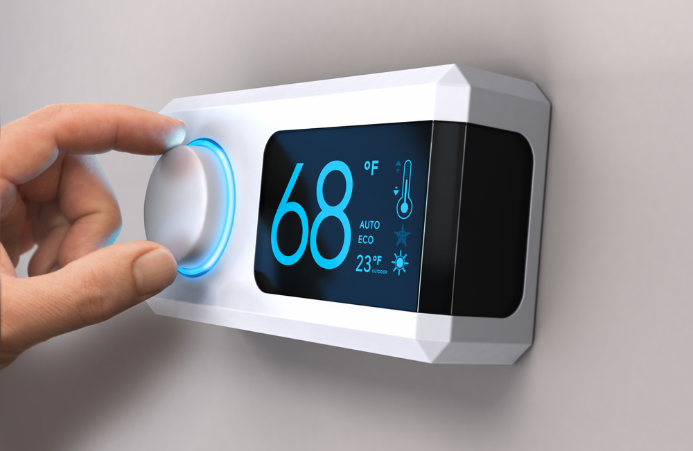 Hand adjusting the temperature on a programmable thermostat