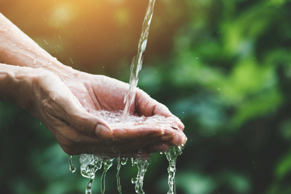 closeup water flow to hand of women for nature concept on the garden background.